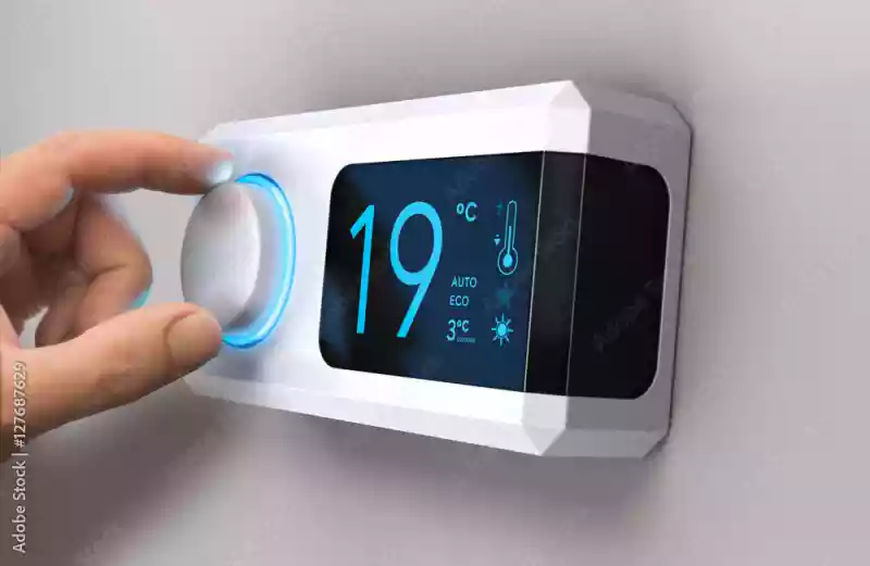 Une photo d'une personne qui regle la température de sa maison